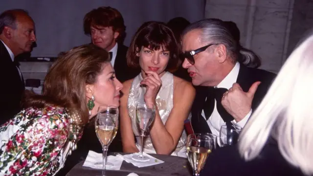 A young Anna Wintour looks at the camera, sat in-between American socialite Susan Gutfreund and German fashion designer Karl Lagerfeld