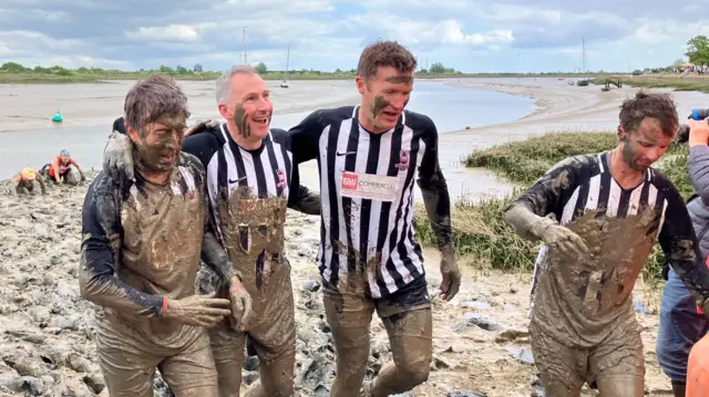 Four men in beacon hill rovers kit wade through the mud