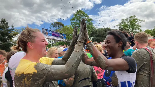 Akylah and Jodie high five. they're covered in mud.