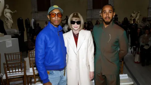 Pharrell Williams, Anna Wintour and Lewis Hamilton smile at the camera.