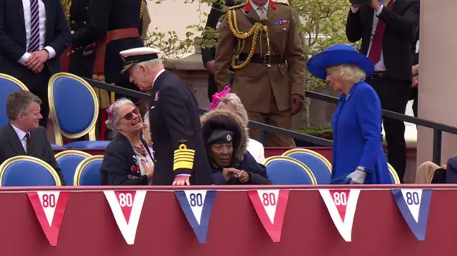 King and Queen walking past rows of seats