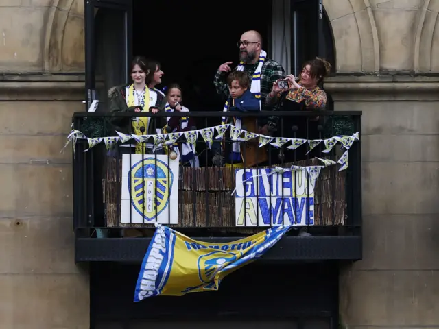 A group of fans get a view of the parade from a balcony