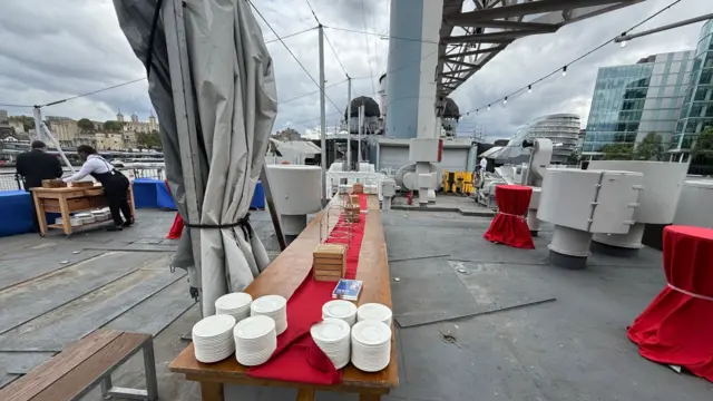 Preparations on HMS Belfast, including a long table with plates