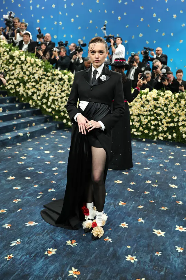 Aimee Lou Wood is suited up at the top and the costume turns into a dress for the lower half.