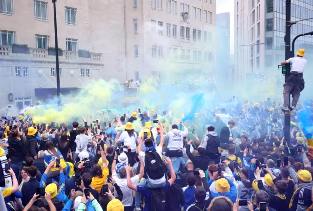 Flare smoke is seen in the air as the buses make their way through Leeds.