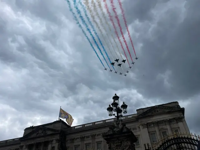 Flypast over Buckingham Palace leaving trails of blue white and red smoke