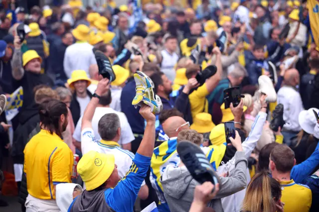 Leeds fans holding their shoes in the air