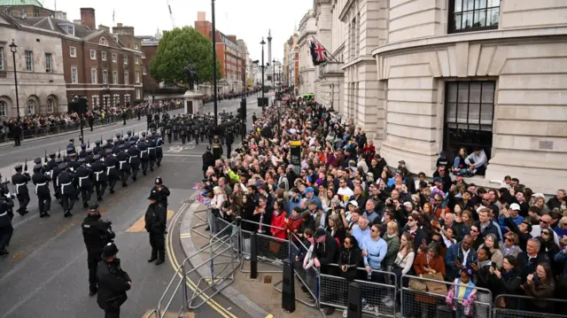 Aerial shot showing crowds packed on pavement behind metal barriers