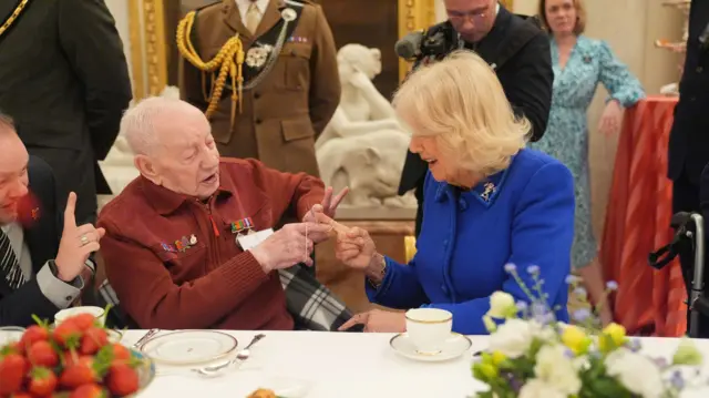 Camilla does magic trick with veteran at dining table