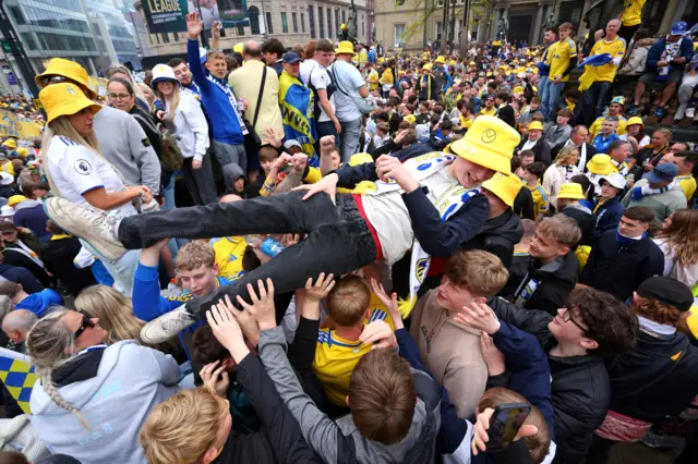 A boy is held aloft by others in a densely packed crowd.