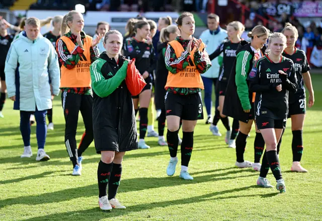 Arsenal players walk dejectedly to applaud the away fans