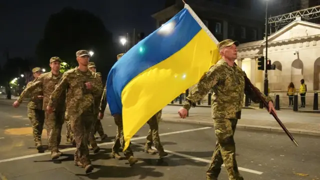 Ukrainian troops carry a Ukrainian flag