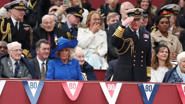 Britain's King Charles salutes next to Queen Camilla