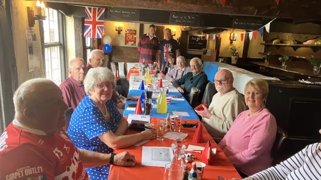 People sit around a pub table decorated in the colours of the Union Jack