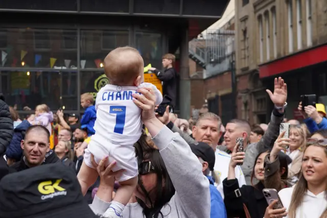 A baby is held aloft by its mother
