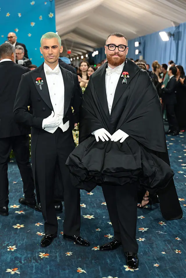 Singer Sam Smith and designer Christian Cowan wearing black suits over white shirts.