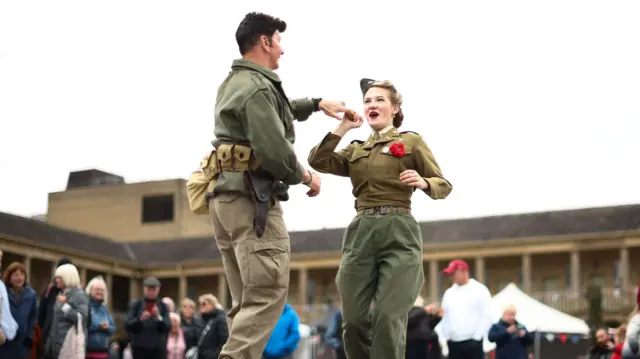 Man and woman dancing together wearing traditional army-style uniform