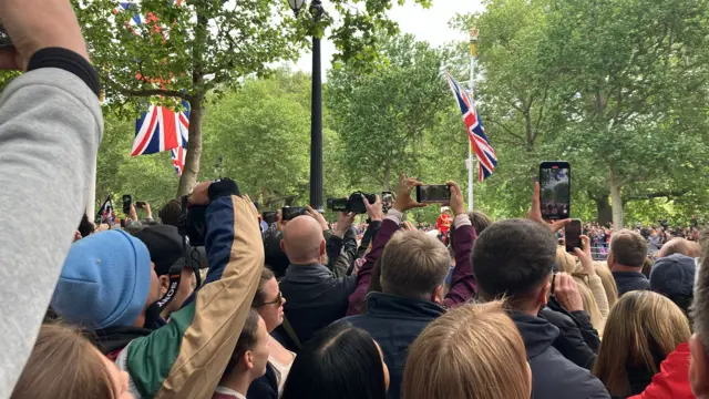 Crowd holding phones up to film parade