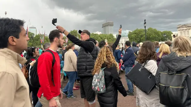 People taking selfies with their phones in the air