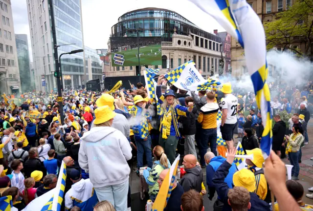 Fans waving blue and yellow Leeds flags in City Square