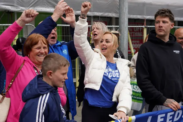 A group of people cheer and wave their hands in the air at the parade.