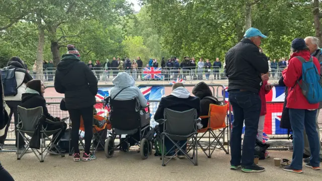 People say in portable chairs behind metal barriers