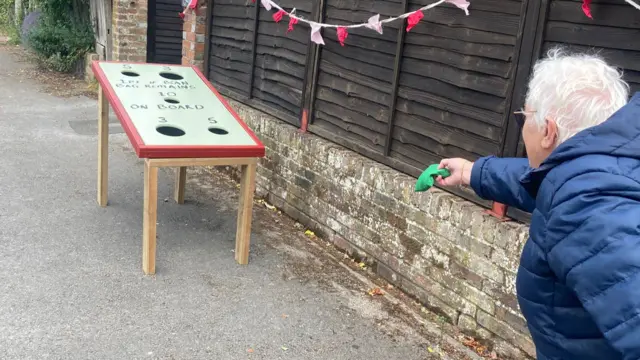 A woman plays a bean bag toss game