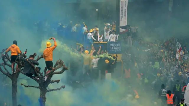 The promotion bus makes its way through a sea of blue and yellow smoke.