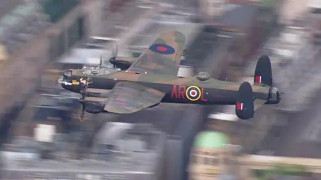 Lancaster Bomber flies over buildings