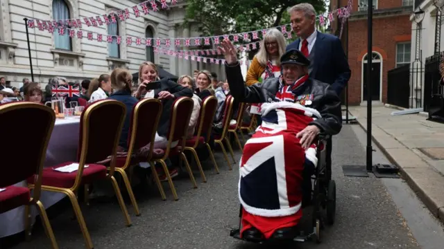World War II veteran Colin Deverell, 101, waves as he arrives at Downing Street for the street party