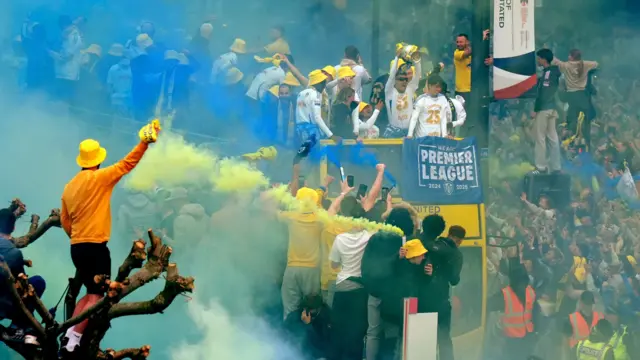 A Leeds United player holds the Championship trophy aloft as fans celebrate.