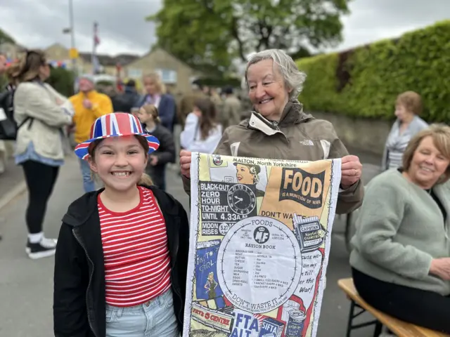 Smiling girl next to woman holding tea towel