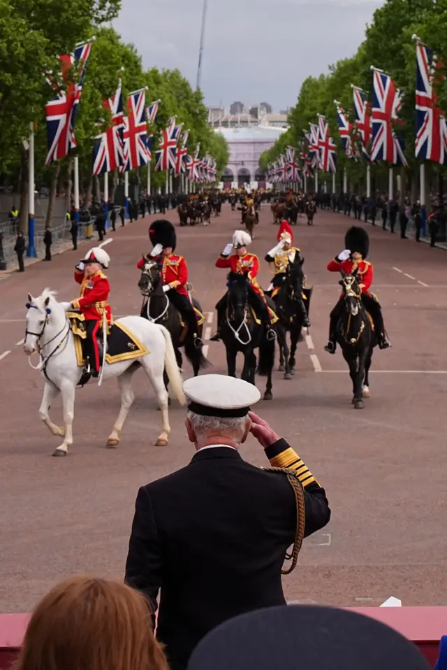 King seen from behind saluting soldiers on horses