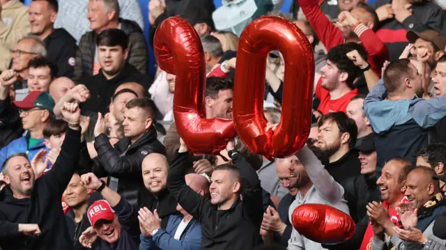 Liverpool fans hold out balloons showing '20' during their game at Chelsea