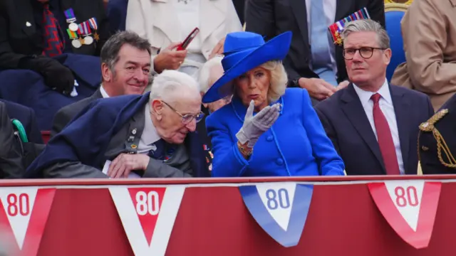 Queen Camilla chats with man in stands, Keir Starmer is next to them