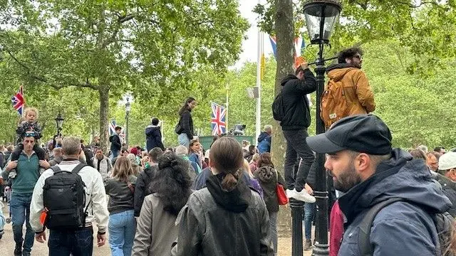 Crowds wait for the procession - some have climbed onto bollards and lamposts
