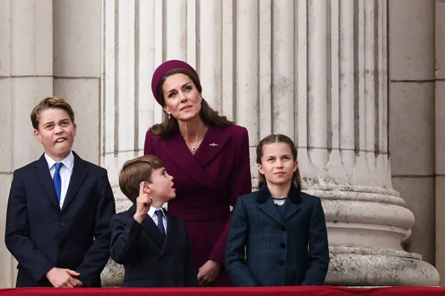 Prince George of Wales, Britain's Prince Louis of Wales, Britain's Catherine, Princess of Wales and Britain's Princess Charlotte of Wales watch the Red Arrows flypast from Buckingham Palace balcony
