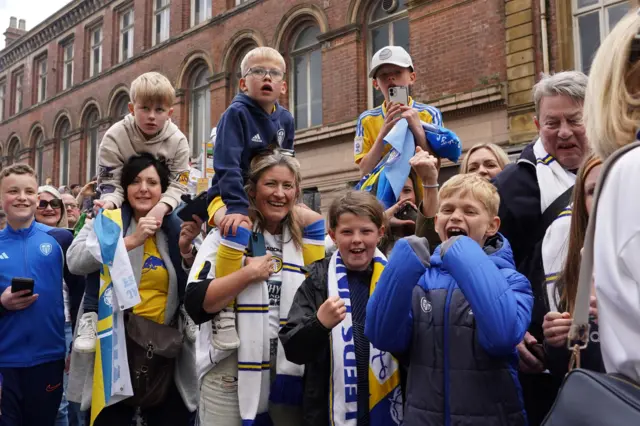 Three young children are held on the shoulders of their mothers at the parade.