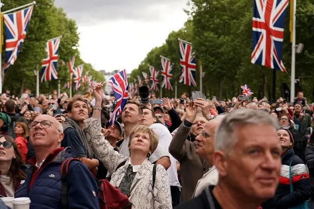 People look up and watch a flypast by RAF aircraft in the Mall