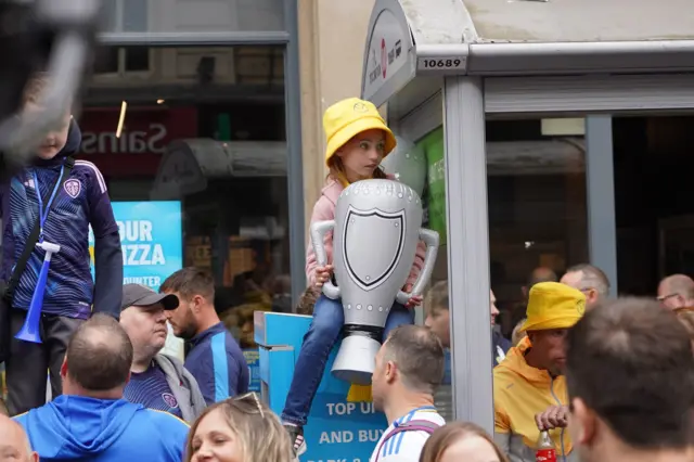 A young girl holds an inflatable trophy