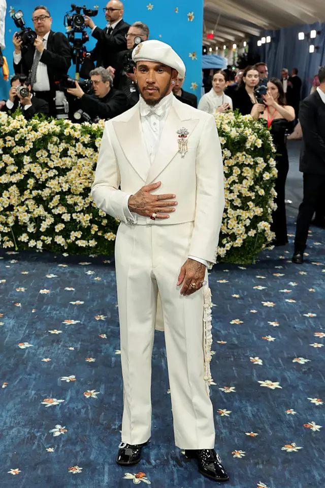 Lewis Hamilton wearing a white tux and white beret at the Met Gala and shiny black shoes.