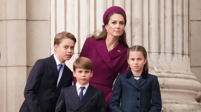 Catherine, William, Louis and Charlotte lean to one side while standing on the balcony