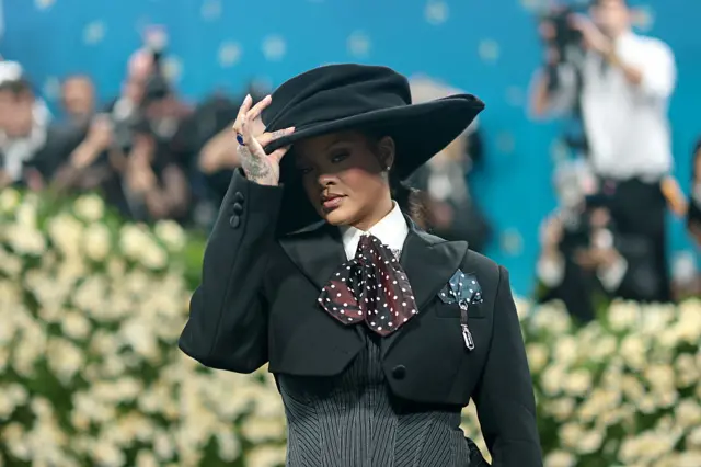 Rihanna wearing all-black dress and a big round black hat