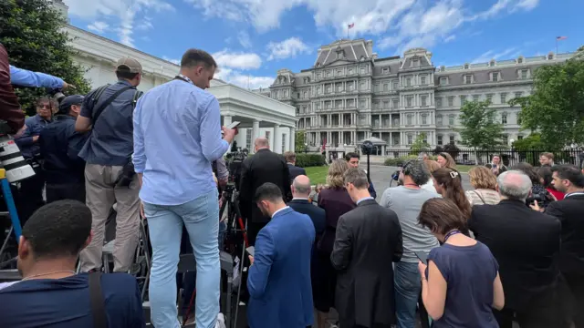 Reporters wait outside the White House
