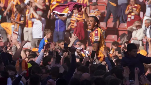 Footballer hoisted aloft by celebrating fans
