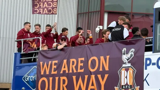Bradford players on bus with banner saying 'we are on our way'.