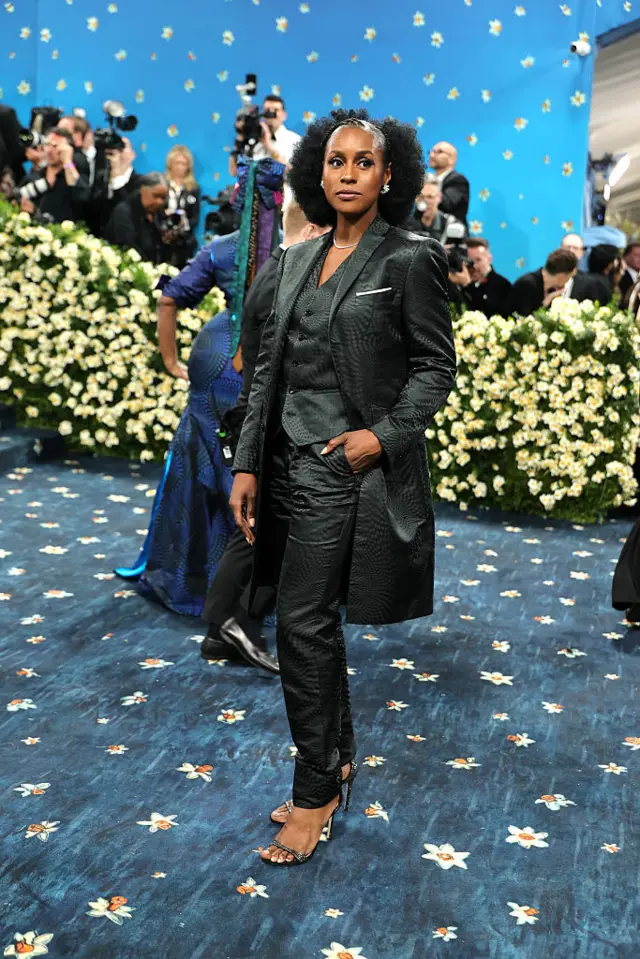 Issa Rae wearing an all black shirt and trousers and a black overcoat