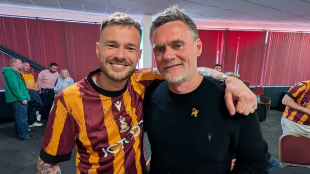 Adam Williams wearing a Bradford City shirt with his arm around Graham Alexander. Both are smiling.