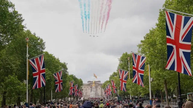The military fly past passes over The Mall and Buckingham Palace, central London. Thousands gather on the treelined street which is bedecked with Union Jack flags
