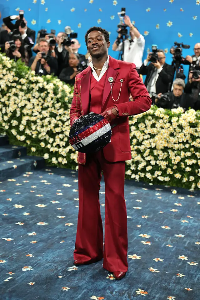 Damon Idris in an all red suit and flared trousers